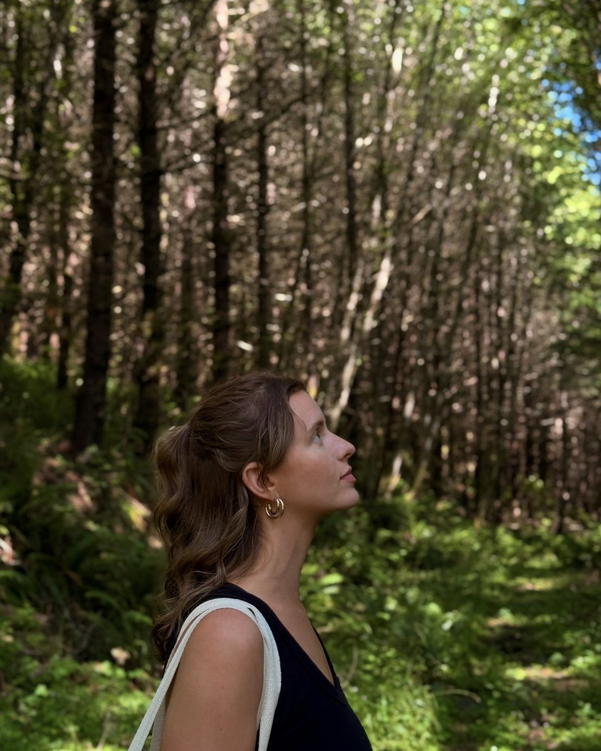 Cyd in a forest, looking up into the trees